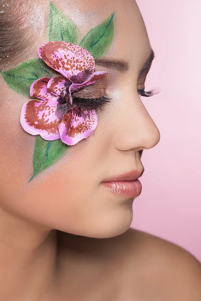 Portret van mooi meisje met bloem op haar gezicht — Stockfoto