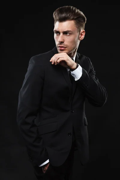Pohledný mladý muž v obleku na tmavém pozadí — Stock fotografie