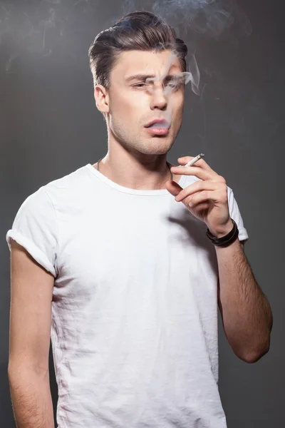 Beau jeune homme fumant de la cigarette — Photo