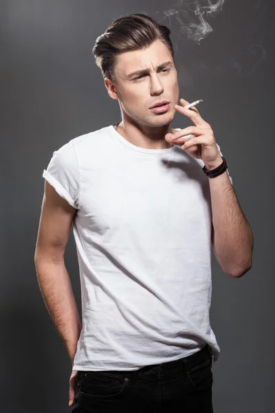 Handsome young man smoking cigarette — Stock Photo, Image