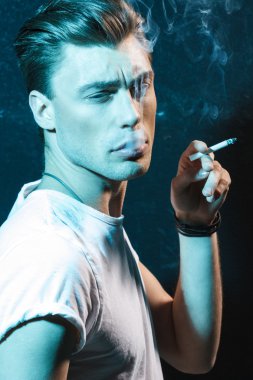 Handsome young man smoking cigarette clipart