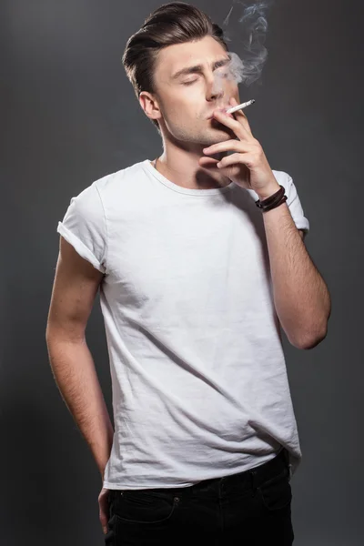 Handsome young man smoking cigarette — Stock Photo, Image