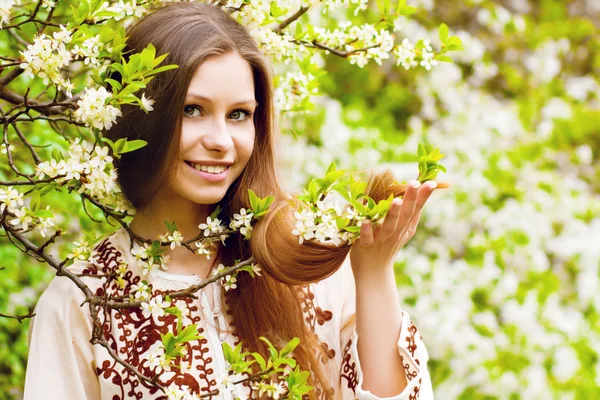 Portret van een prachtige lente meisje in kersenboom bloemen. — Stockfoto