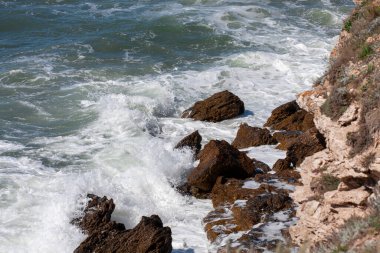 Okyanus dalgası kayalık bir kıyıya çarpar. Açık deniz köpüğü kıyıya vurdu.