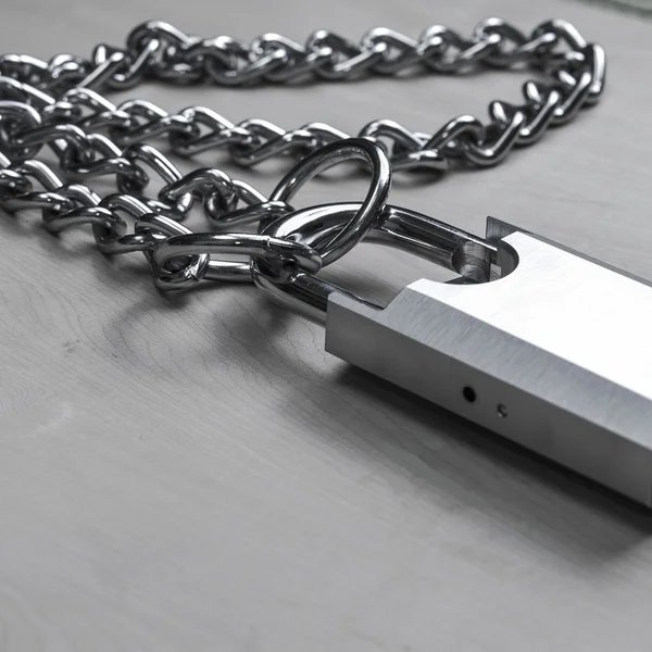 Padlock and chain on wooden table, black and white — Stock Photo, Image