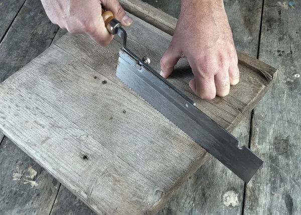 Carpintero trabajando en una sierra de mano tablas de cortar en su taller — Foto de Stock