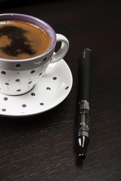 Чашка кофе и электронная сигарета на столе — стоковое фото
