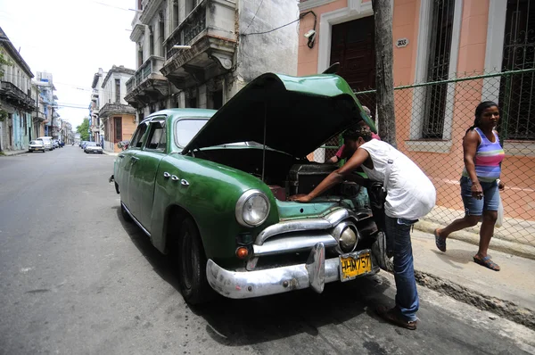 Een man herstellen zorgvuldig zijn oude Amerikaanse auto op straat — Stockfoto