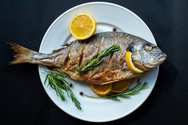 Dorado balığının iştah açıcı üst görüntüsü. Limon ve biberiyeli bir tabakta kızarmış deniz balığı..