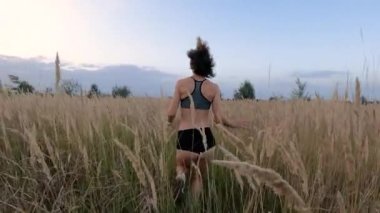 A beautiful girl in short shorts and a top runs across the field. Slow motion.