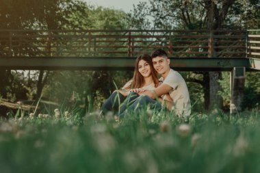 Birbirini seven iki genç çimenlerin üzerinde oturuyor..