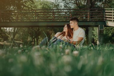 Birbirini seven iki genç çimenlerin üzerinde oturuyor..