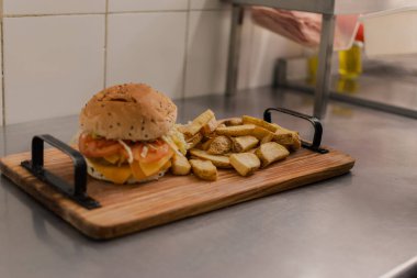 A big double burger with fries in the kitchen.