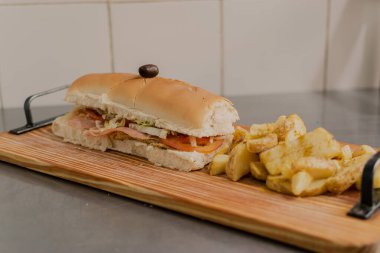 A big Sandwich with fries on the table.