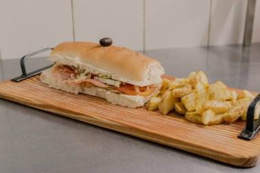 A big Sandwich with fries on the table.