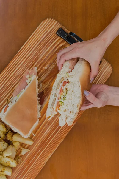 Жінка Тримає Великий Бутерброд Картоплею Столі — стокове фото