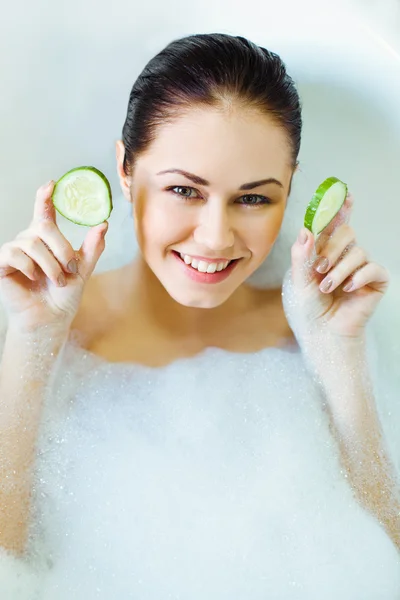 Attractive young woman lying in the bath with cucumber mask — Stock Photo, Image