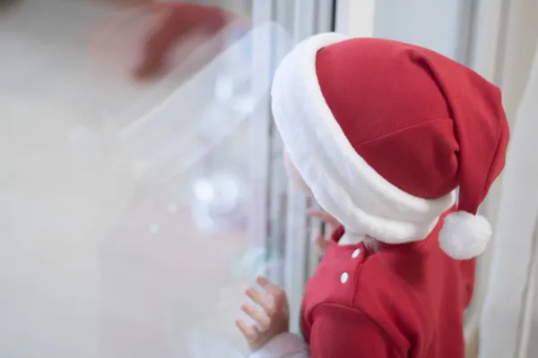 Ein Kind im roten Weihnachtskostüm in Vorfreude auf das Fest, künstlerisches Filmkorn Stockbild