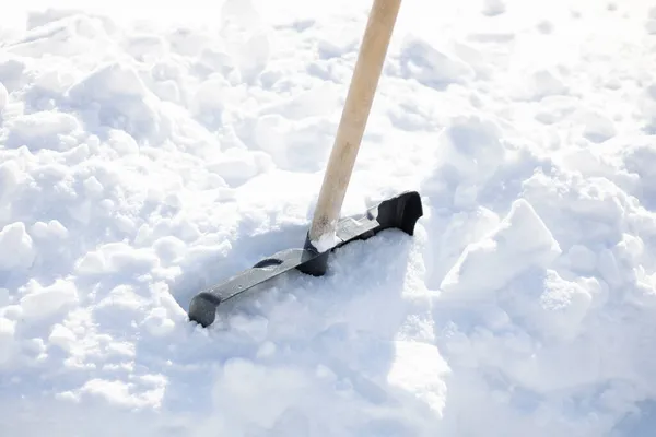 Eine Schaufel in einer Schneewehe, eine Schaufel in der Mitte vor einem Hintergrund aus Schnee Stockbild