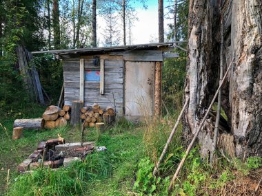 Ormandaki ahşap kulübe. Avcılar sık bir ormanın arka planına karşı barakada.