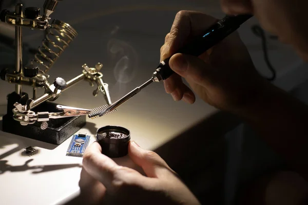 Atölyede teknisyen mühendisi. Lehim demiri, lehim, lehim, lehimleme istasyonu ve diğer aksesuarları kullanarak onaran askerler var..