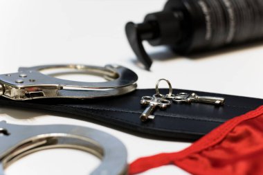 Leather paddle and handcuffs with keys and womens panties on a white background, the concept of sex.