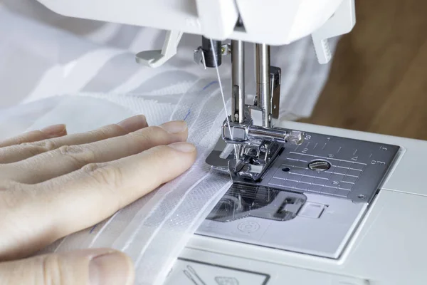 Hemming the edges of the curtains with curtain tape on a sewing machine. lizenzfreie Stockbilder