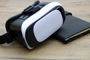 Sanal gerçeklik gözlükleri ahşap bir masanın üzerindeki defterin üzerinde duruyor. Yeni teknolojiler