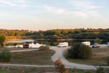 Camper vans and motorhomes living van life social distancing on a calm landscape by Nisa Dam in Alentejo, Portugal at sunset