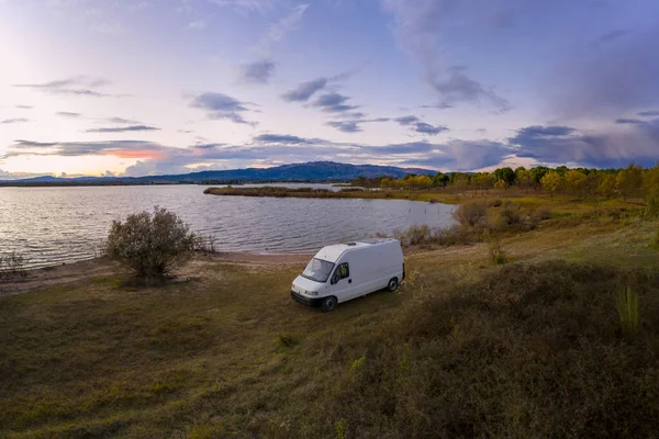 Lake drone aerial view of a camper van with solar panel living van life mountain panorama landscape at sunset in Marateca Dam in Castelo Branco, Portugal