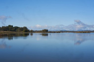 Lake dam landscape with reflection of Gardunha mountains and trees on a cloudy day in Santa Agueda Marateca Dam in Portugal