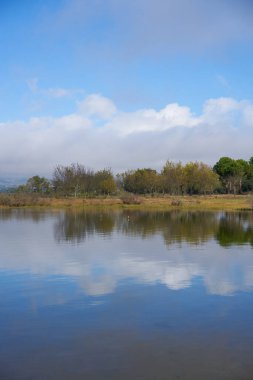 Lake dam landscape with reflection of Gardunha mountains and trees on a cloudy day in Santa Agueda Marateca Dam in Portugal