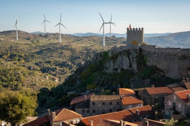 Portekiz 'deki Sortelha kalesinin, antik taş evlerin ve rüzgar türbinlerinin manzarası.