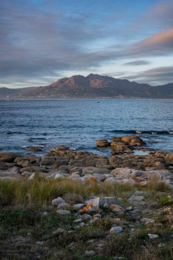 Caldebarcos, İspanya 'nın Galiçya kentindeki Atlantik Okyanusu ile gün batımında dağlarla manzaralı bir manzara.