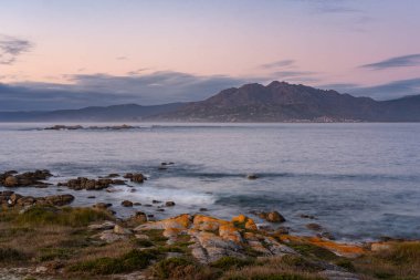 Caldebarcos, İspanya 'nın Galiçya kentindeki Atlantik Okyanusu ile gün batımında dağlarla manzaralı bir manzara.
