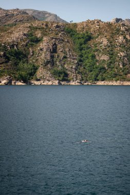 Portekiz, Geres Ulusal Parkı 'ndaki Vilarinho das Furnas Barajı' nda gölde yüzen beyaz bir adam.