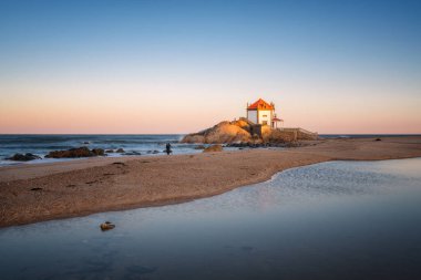 Capela do Senhor da Pedra 'yı Portekiz' in Miramar şehrinde gün batımında çeken adam.
