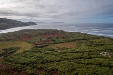 İnsansız hava aracı panoramik görüntüsü, Galiçya, İspanya 'daki Tourinan Burnu' nda Atlantik Okyanusu ile yeşil ve kırmızı bir manzara.