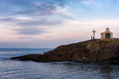 Günbatımını gören turistler, Fransa 'nın güneyindeki Collioure' daki Saint Vincent Şapeli 'nin haçı yakınında.