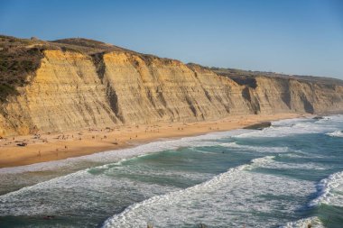 Portekiz, Sintra 'da sörf yapan sörfçülerle dolu Magoito plajı.