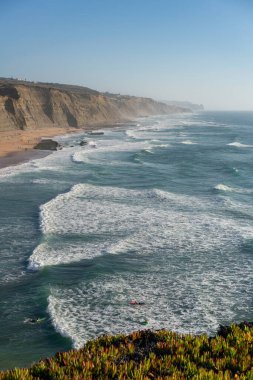 Portekiz, Sintra 'da sörf yapan sörfçülerle dolu Magoito plajı.