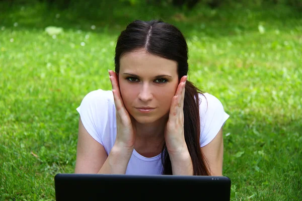 Mooie jonge student met behulp van laptop op gras — Stockfoto