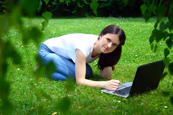Hermosa joven estudiante usando el ordenador portátil en la hierba —  Fotos de Stock