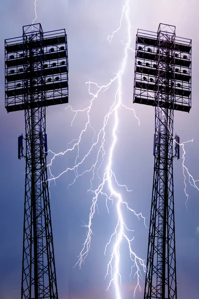 Spotlights on a lighting mast over the stadium against the blue sky with white clouds on a day
