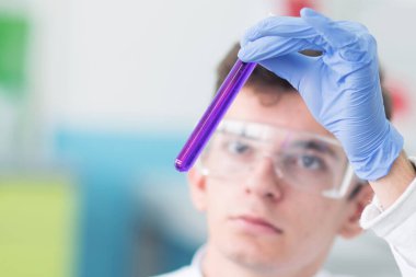 İki genç bilim adamı bir labirentteki mikroskoba bakıyorlar.