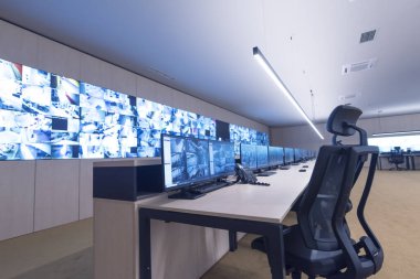 Güvenlik görevlisi gözetleme odasındaki modern güvenlik kameralarını izliyor.