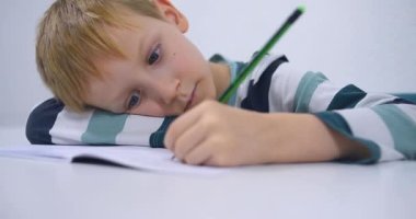 Okullu çocuk evde alfabe yazma alıştırması yapıyor. Çocuk çocuk yazıyor. Ev ödevi.