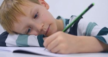 Okullu çocuk evde alfabe yazma alıştırması yapıyor. Çocuk çocuk yazıyor. Ev ödevi.