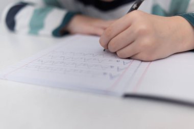 Okullu çocuk evde alfabe yazma alıştırması yapıyor. Çocuk çocuk yazıyor. Ev ödevi.