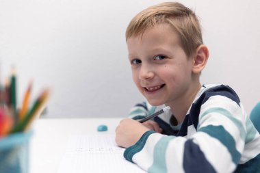 Okullu çocuk evde alfabe yazma alıştırması yapıyor. Çocuk çocuk yazıyor. Ev ödevi.